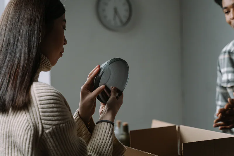 Una mujer desempaca y revisa la vajilla recién recibida.